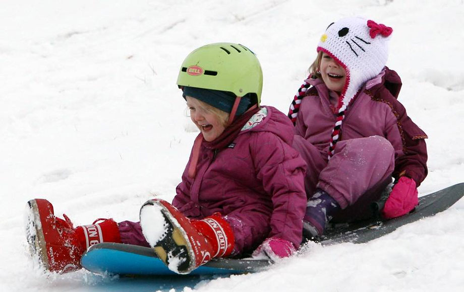Kids sledding down a hill at Camel's Back park. The hill at Camels Back park is super popular for sledding, since it's the steepest slope in town.